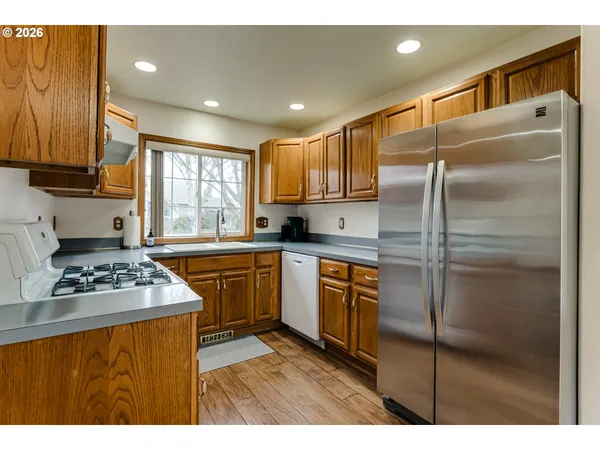 a kitchen with kitchen island granite countertop stainless steel appliances a sink stove refrigerator and cabinets