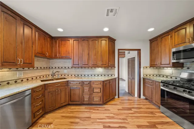 a kitchen with stainless steel appliances granite countertop a stove a sink dishwasher and a refrigerator