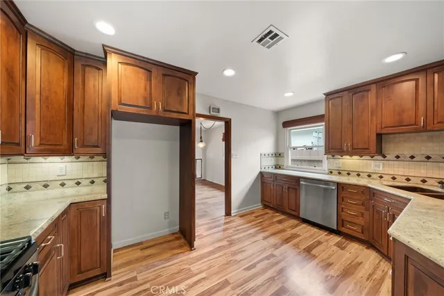 a kitchen with stainless steel appliances granite countertop a refrigerator a sink dishwasher a stove with wooden cabinets and floor