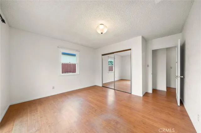 a view of an empty room with wooden floor and closet