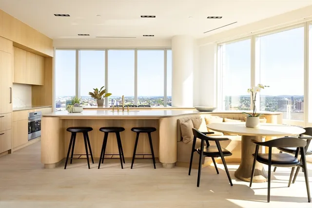 a dining hall with stainless steel appliances kitchen island a table and chairs in it