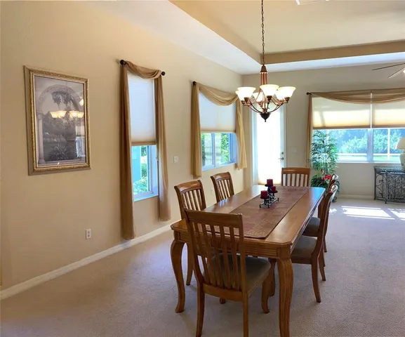 a view of a dining room with furniture a chandelier and large windows