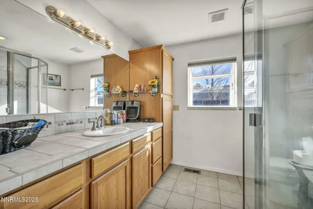 a spacious bathroom with a granite countertop sink a toilet a mirror and shower