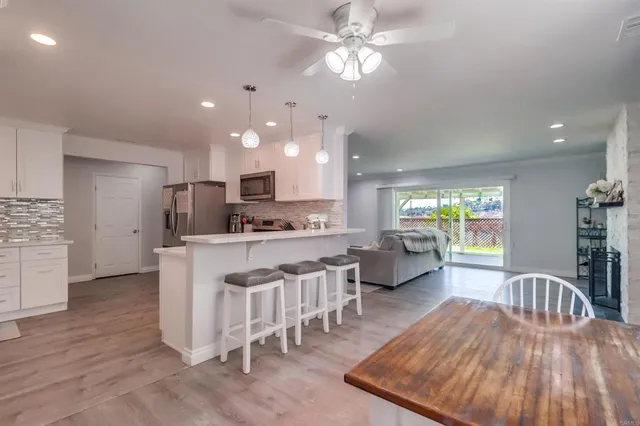 a living room with stainless steel appliances kitchen island granite countertop furniture a rug kitchen view and a chandelier