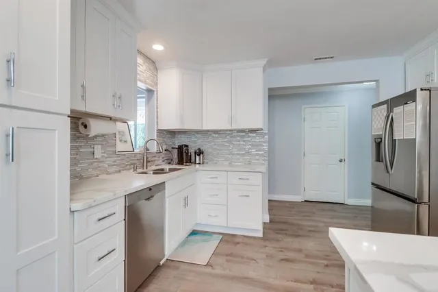 a kitchen with white cabinets and stainless steel appliances