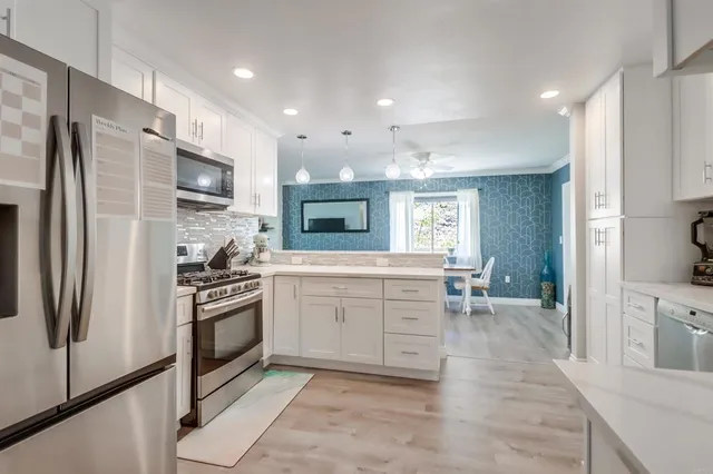 a kitchen with granite countertop a refrigerator stove top oven and sink