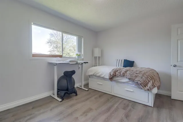 a bedroom with a bed chair and windows