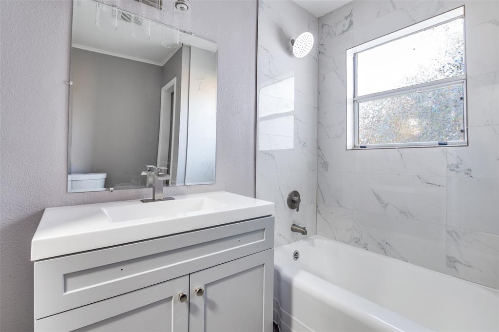 421 West 8th Street Lancaster, TX 75146 - Photo 22 of 25 a bathroom with a sink a bathtub and a mirror