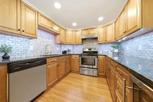 a kitchen with granite countertop a sink cabinets stainless steel appliances and a counter space