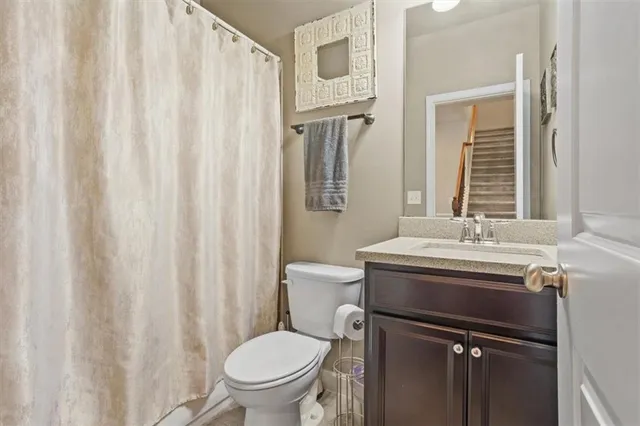 a bathroom with a granite countertop sink a toilet and a mirror