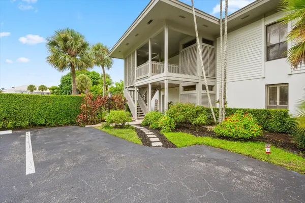 a view of yellow house with a yard and potted plants