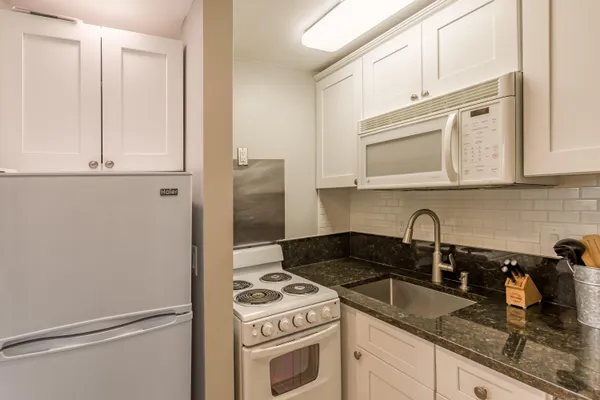 a kitchen with stainless steel appliances granite countertop white cabinets and a stove