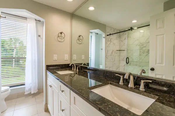 a bathroom with a granite countertop double vanity sink a mirror and a bathtub