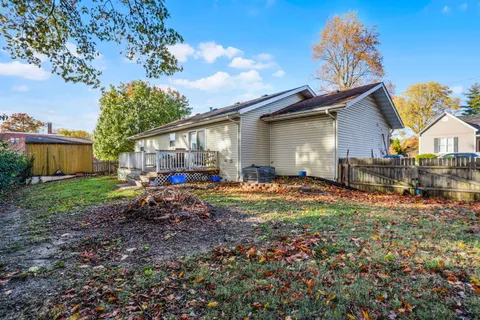 a view of backyard of house with wooden fence and large trees