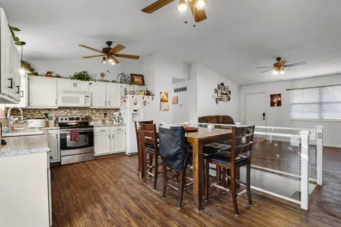 a kitchen with stainless steel appliances a table and chairs in it