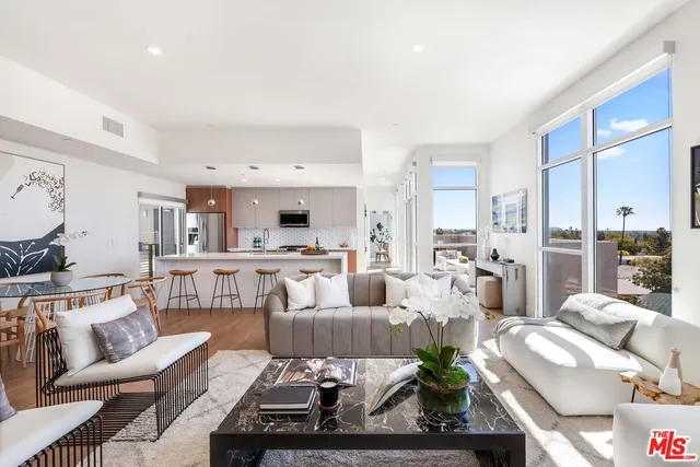 a living room with furniture kitchen view and large windows
