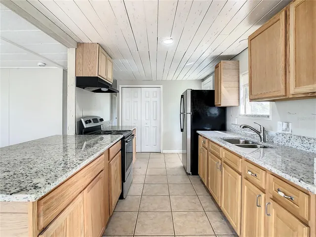 a large kitchen with stainless steel appliances granite countertop a sink stove and refrigerator