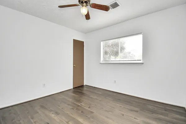 an empty room with a window and a ceiling fan