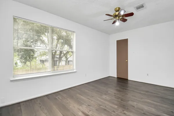 a view of an empty room with a window and wooden floor