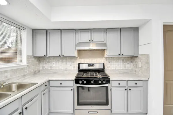 a kitchen with white cabinets and appliances