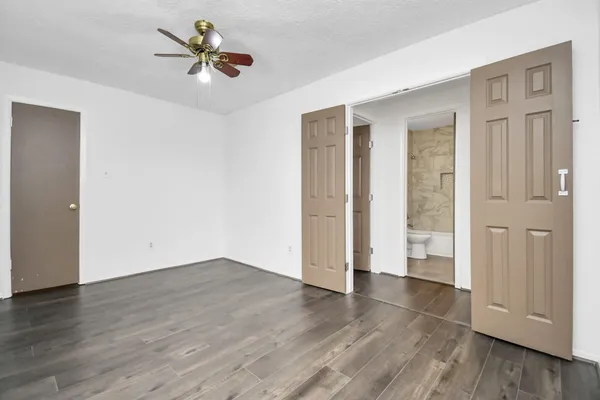 an empty room with wooden floor and ceiling fan