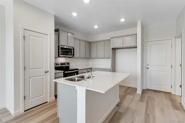 a kitchen that has a sink a microwave a refrigerator and cabinets