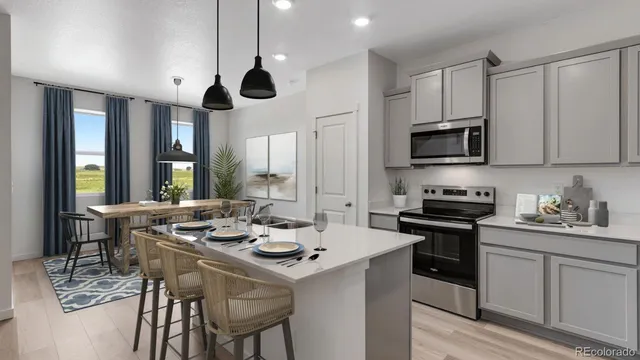 a kitchen with stainless steel appliances a stove a sink a microwave a dining table and chairs with wooden floor