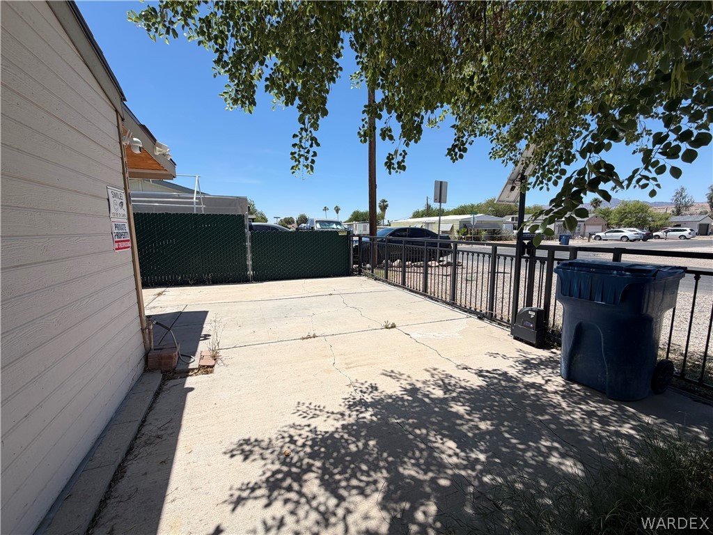1910 Rio Grande Road Bullhead City, AZ 86442 - Photo 4 of 29 Paved outdoor area featuring a black metal fence and an adjacent building with horizontal siding