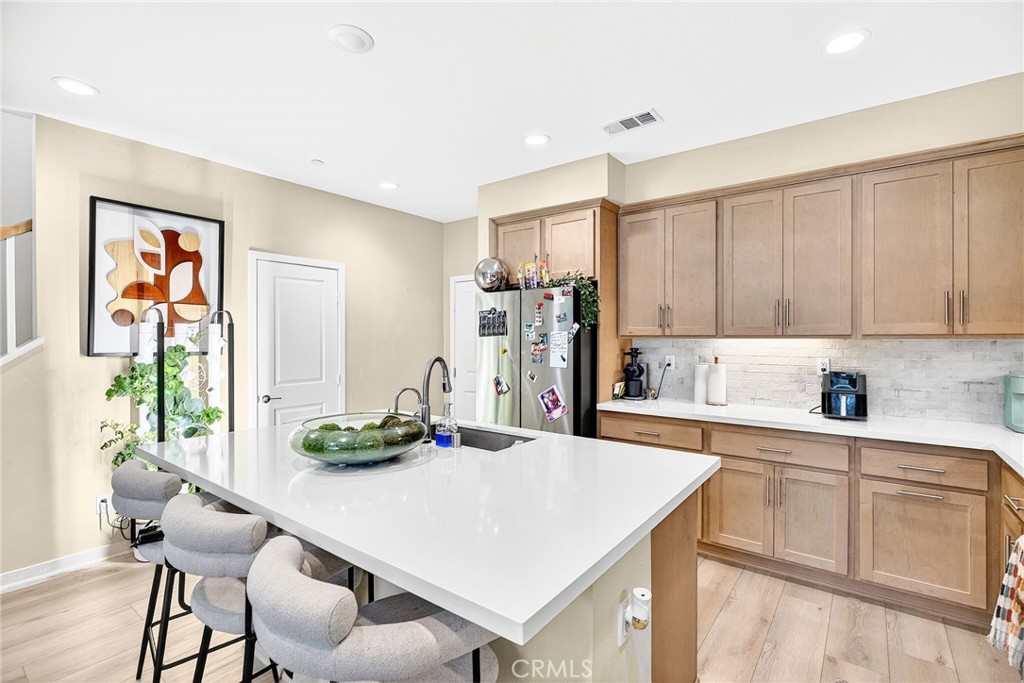 39400 Corvina Lane Temecula, CA 92591 - Photo 12 of 42 a kitchen with stainless steel appliances kitchen island granite countertop a table chairs in it and white cabinets