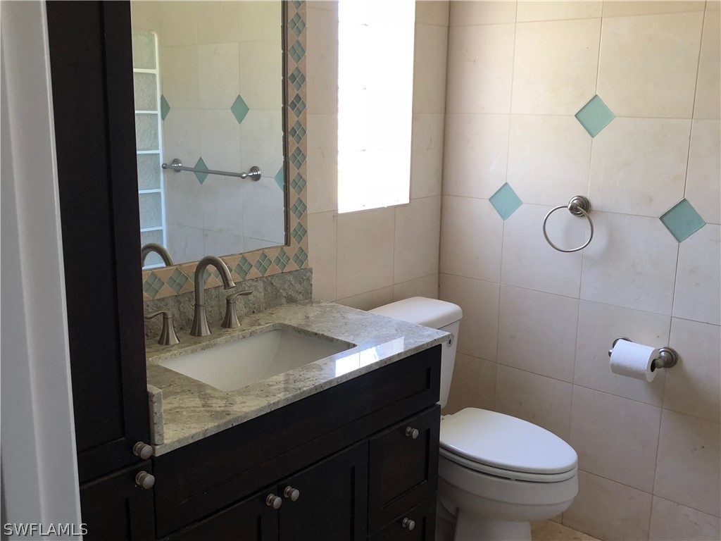 7535 Morgan Road Fort Myers, FL 33967 - Photo 15 of 19 a bathroom with a granite countertop sink a toilet and a mirror