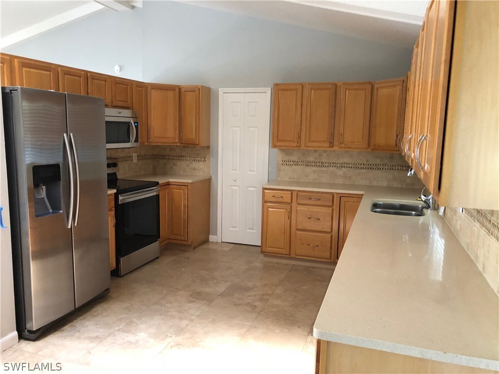 7535 Morgan Road Fort Myers, FL 33967 - Photo 7 of 19 a kitchen with stainless steel appliances granite countertop a refrigerator a stove and a sink with wooden cabinets