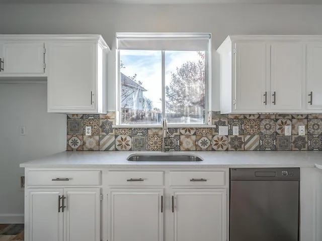 a sink with white cabinets and a window