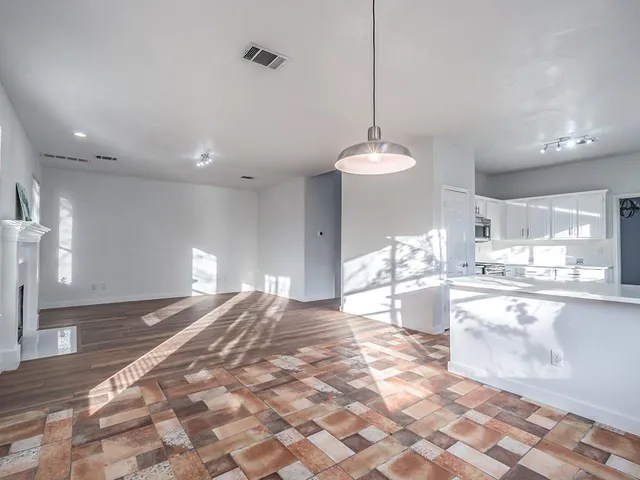 a open kitchen with stainless steel appliances granite countertop a sink dishwasher a stove a dining table and chairs with wooden floor