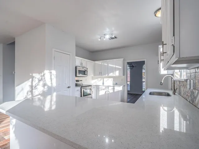 a view of an empty room with a window and a kitchen