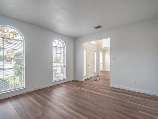 a view of an empty room with wooden floor and a window