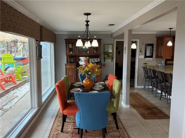 a dining room filled with furniture a chandelier and wooden floor