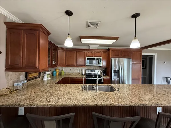 a dining hall with stainless steel appliances granite countertop a stove a sink a dining table and chairs with the floor to ceiling window