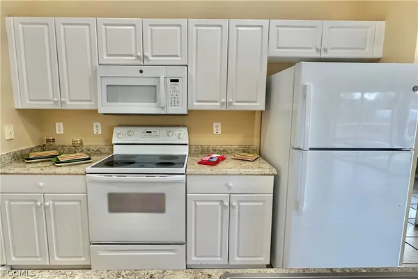 a kitchen with granite countertop cabinets and white appliances