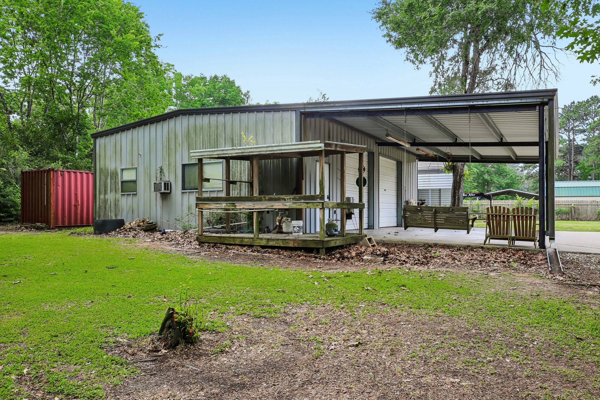 164 Frank Road Trinity, TX 75862 - Photo 8 of 20 The exterior of the workshop and outbuildings emphasizes functionality, with a dedicated outdoor workstation and plenty of covered space for tools and heavy equipment.