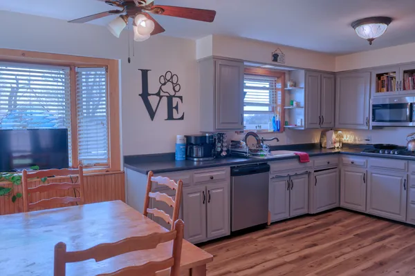 a kitchen with stainless steel appliances granite countertop a sink cabinets and wooden floor