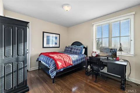 a bedroom with a bed table chair and a window