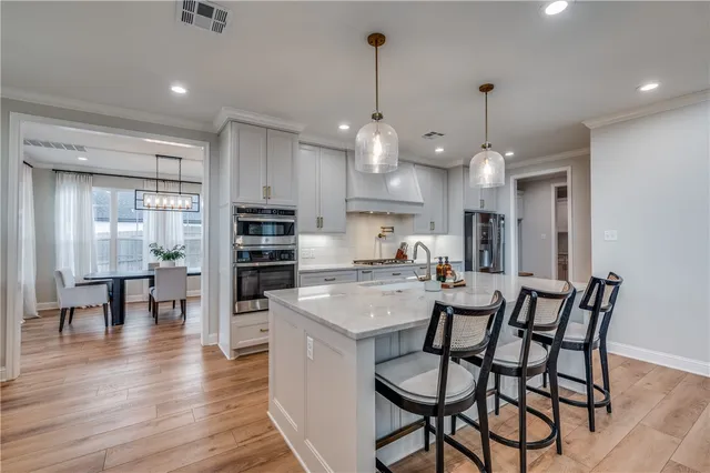 a view of a dining room and livingroom with furniture wooden floor kitchen chandelier