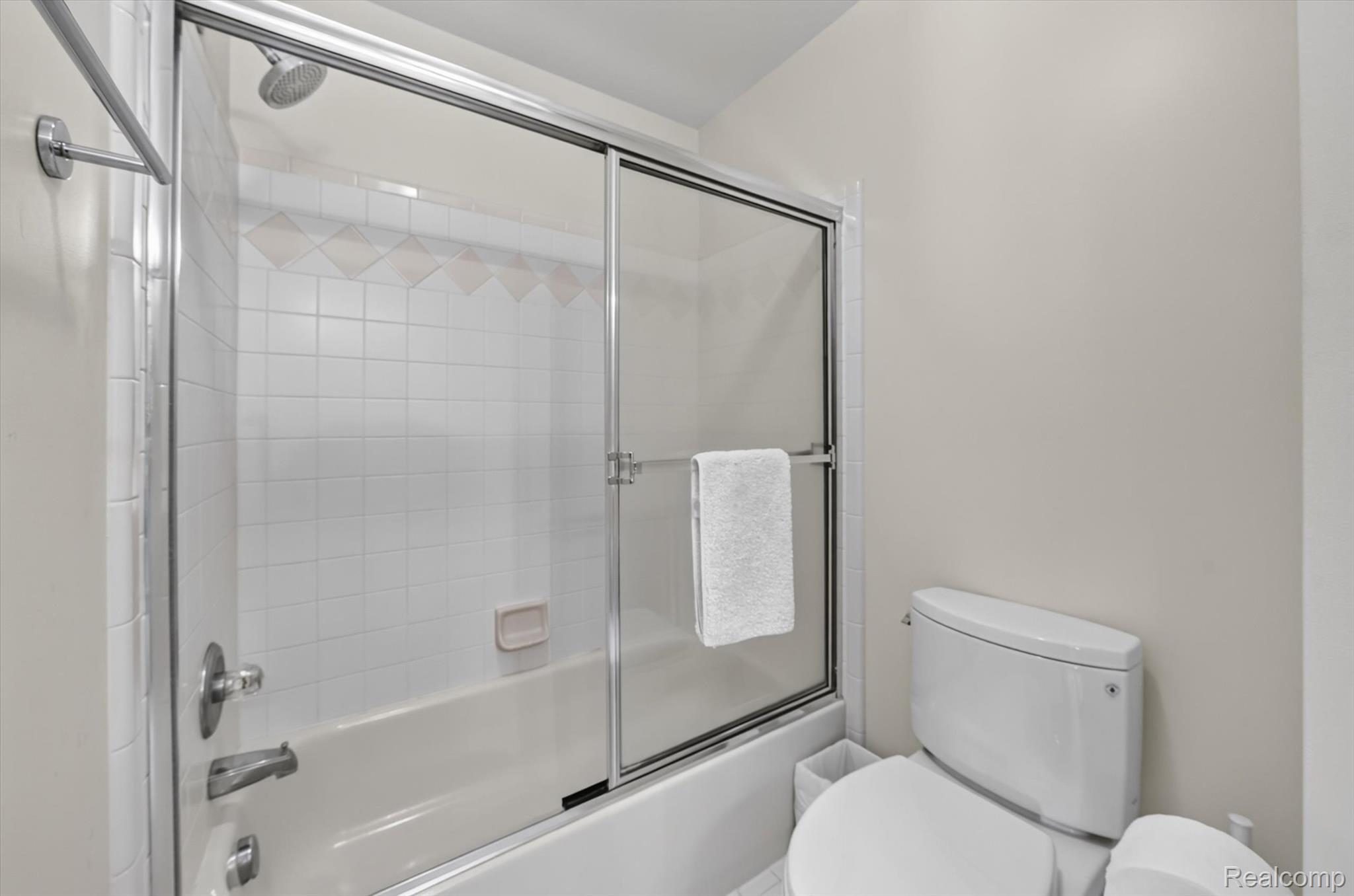 3804 Elk Drive Rochester, MI 48306 - Photo 31 of 75 Full-size tub with sliding glass shower enclosure, chrome fixtures, and white tile surround with decorative accent band