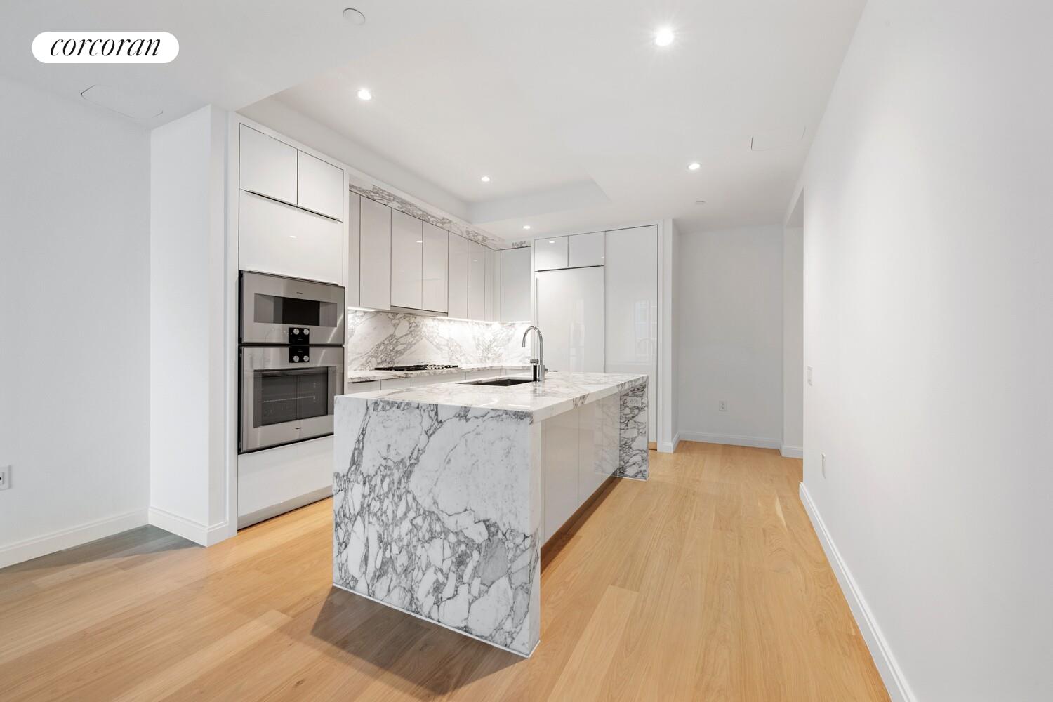 10 Riverside Boulevard, Unit 27C Manhattan, NY 10069 - Photo 4 of 14 a large kitchen with stainless steel appliances kitchen island granite countertop a refrigerator oven a sink dishwasher and white cabinets with wooden floor