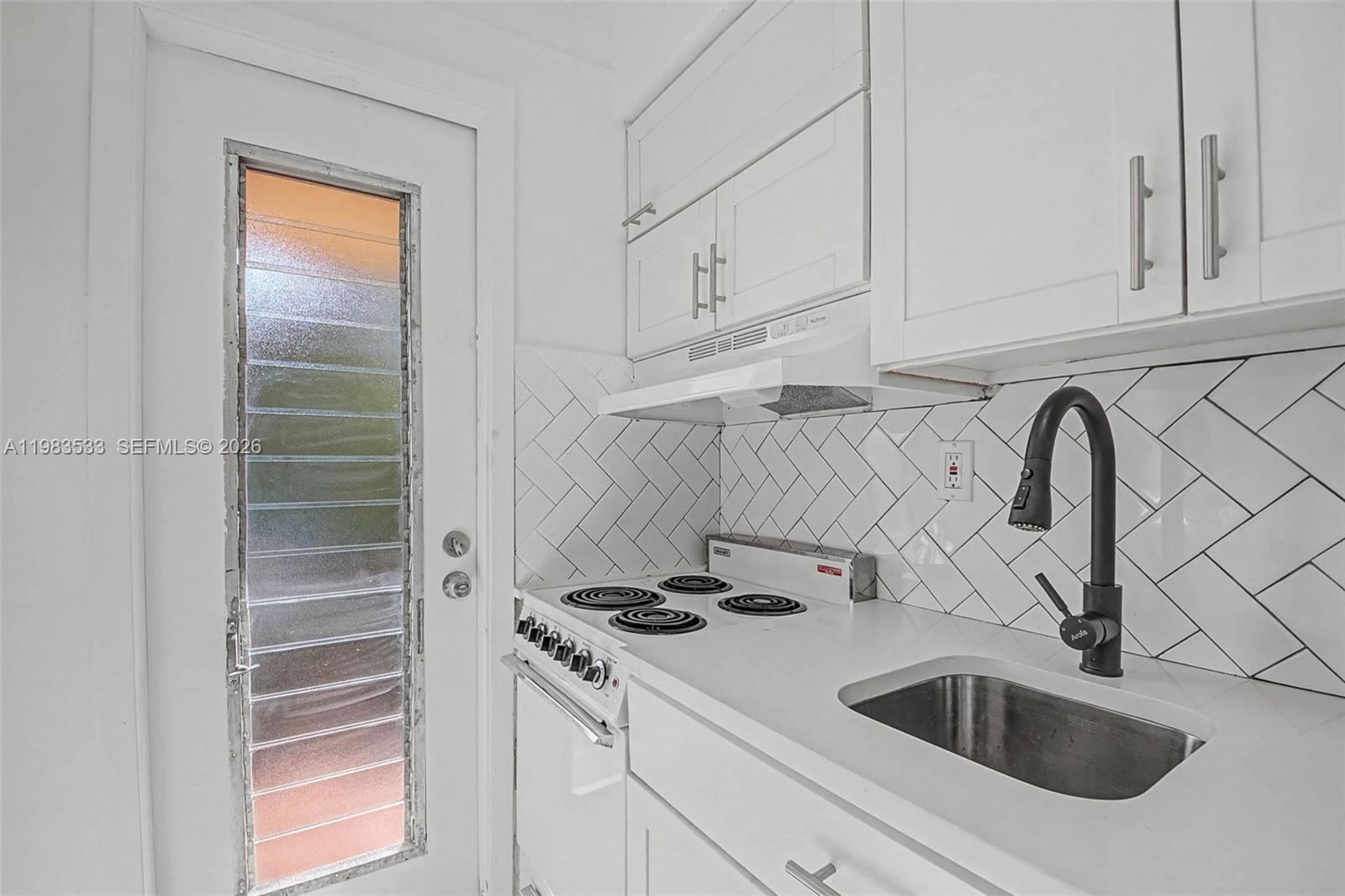60 Northwest 79th Street, Unit 10 Miami, FL 33150 - Photo 2 of 18 a kitchen with white cabinets and a sink