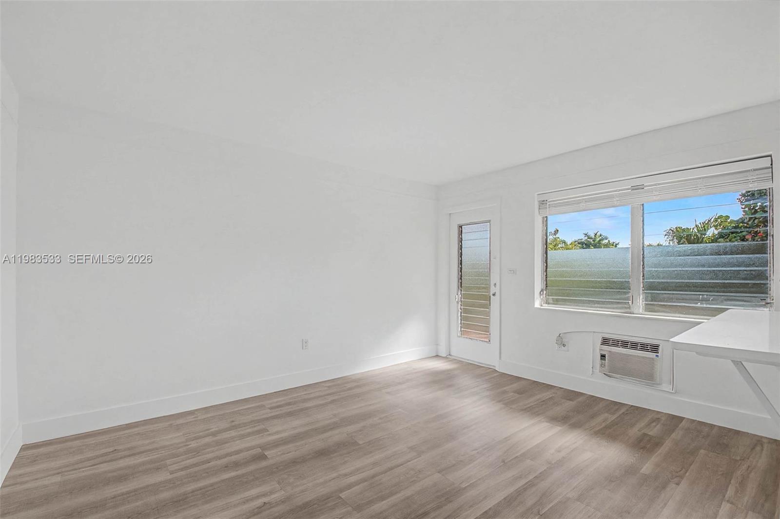 60 Northwest 79th Street, Unit 10 Miami, FL 33150 - Photo 4 of 18 an empty room with wooden floor and windows