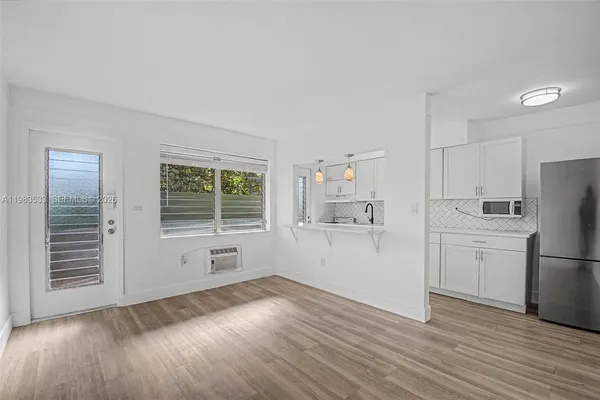 a kitchen with a refrigerator a stove top oven and wooden floors