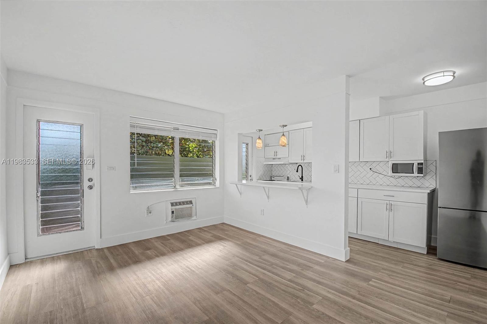 60 Northwest 79th Street, Unit 10 Miami, FL 33150 - Photo 6 of 18 a kitchen with a refrigerator a stove top oven and wooden floors