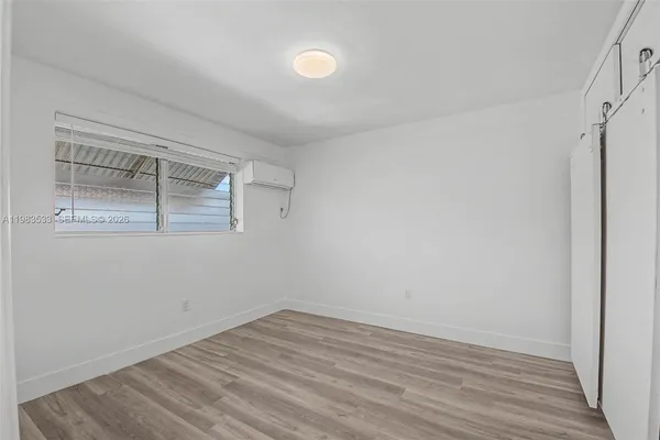 a view of a room that has wooden floor and a window