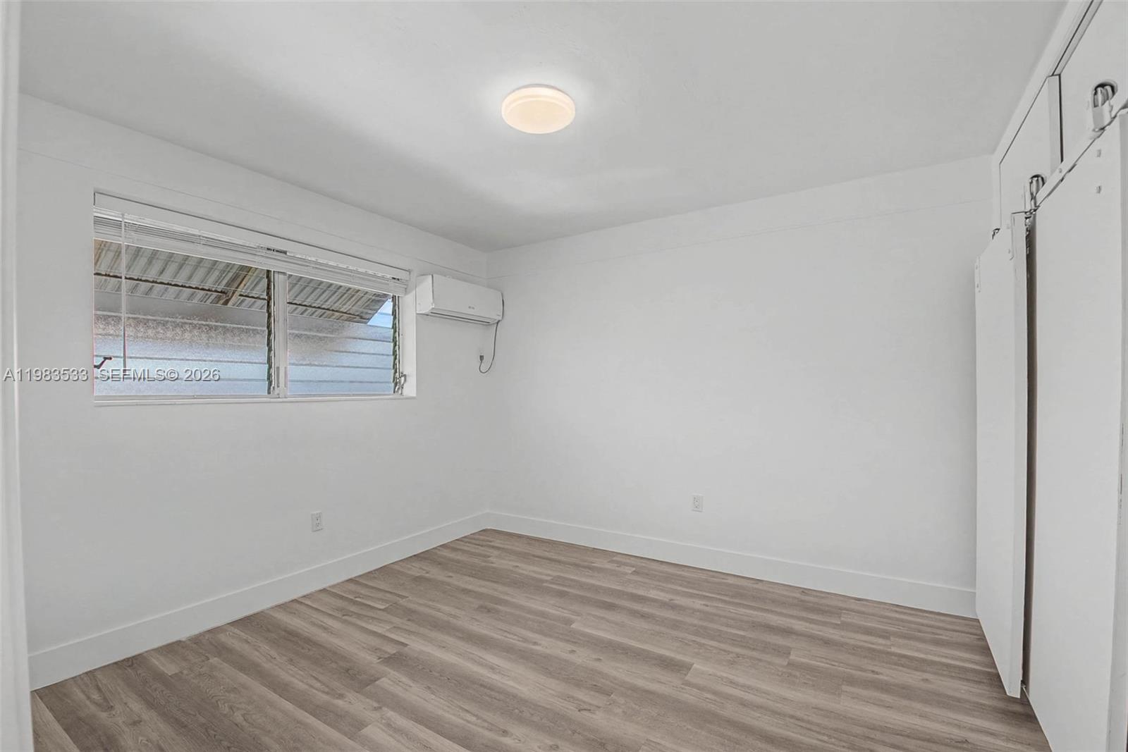60 Northwest 79th Street, Unit 10 Miami, FL 33150 - Photo 7 of 18 a view of a room that has wooden floor and a window